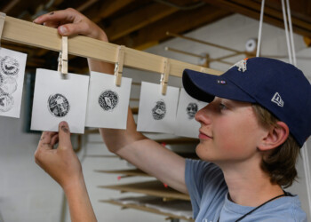 A high school intern hangs up his wood engraving print to dry.