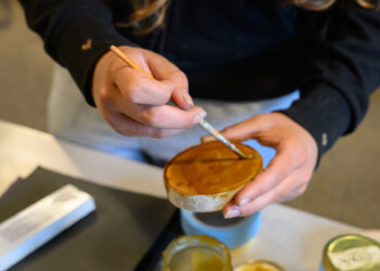 A bug paste is applied to wooden cookies before the engraving process begins.